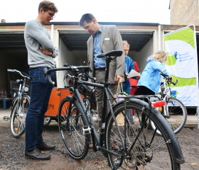 Das Foto (Kreisverwaltung Germersheim, Michael d’Aguiar, zur Veröffentlichung freigegeben) zeigt einen Mitarbeiter der Kreisverwaltung (links) der täglich mit dem Fahrrad zur Arbeit pendelt und Büroleiter Ralph Lehr (Mitte). Die Kreisverwaltung ist die ei