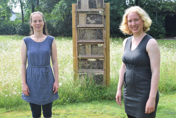 Neustart für „Plietsch fürs Klima“ (v. l.): Klimaschutzmanagerin Eva Teckenburg und „Plietsch fürs Klima“-Koordinatorin Juliane Höhle stehen vor dem Insektenhotel auf der Grünfläche am Kreishaus. Das Insektenhotel wurde von Schüler*innen der Friedrich-Elv