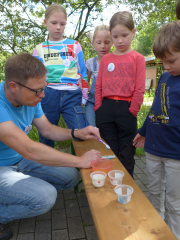 Axel Natsch vom Imkerverein Gütersloh erklärt den Kindern das Wildbienenspiel: In einem Wettlauf schlüpften die Kinder in die Rolle der Wildbienen und bauten eine Niströhre mit einzelnen Kammern für ihren Nachwuchs.