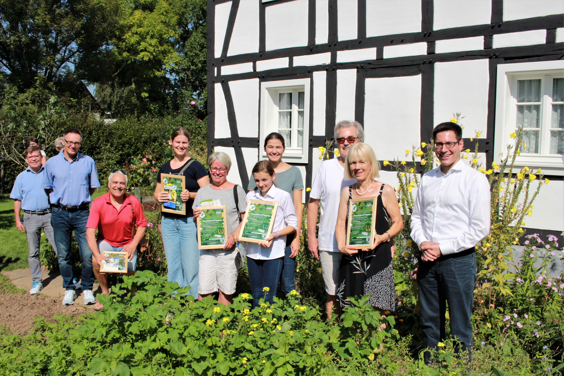 Die strahlenden Gewinnerinnen und Gewinner (Mitte) bei der Preisverleihung mit Bürgermeister Max Leitterstorf (re.) und dem Technischen Beigeordneten Rainer Gleß (2.v.l.) im Garten von Regina Michels in Sankt Augustin-Birlinghoven.