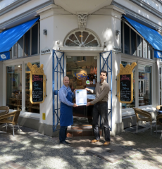 Übergabe der Urkunde und der Ökostrom-Plakette an den Inhaber von Käse Friese, Karim Olivo, durch KMU-Klimaschutzmanager Ataman Erönü. Foto: Stadt Oldenburg