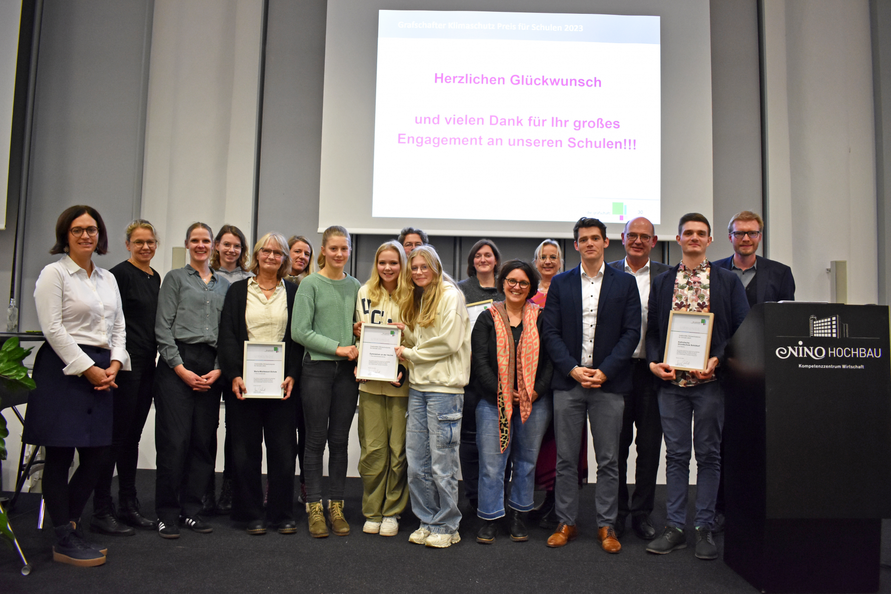 Landrat Uwe Fietzek (3.v.r.), Klimaschutzmanager Stephan Griesehop (r.) und Jacqueline Demelis (Wirtschaftsförderung, l.) mit den Gewinnerinnen und Gewinnern des Klimaschutz-Schulpreises am 6. Dezember 2023 bei der Auszeichnung im Nordhorner NINO-Hochbau.