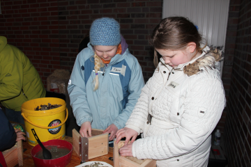 Konzentriert schichten diese beiden Teilnehmerinnen die Holzröhrchen so dicht wie möglich in den Dachgiebel der Nisthilfe.