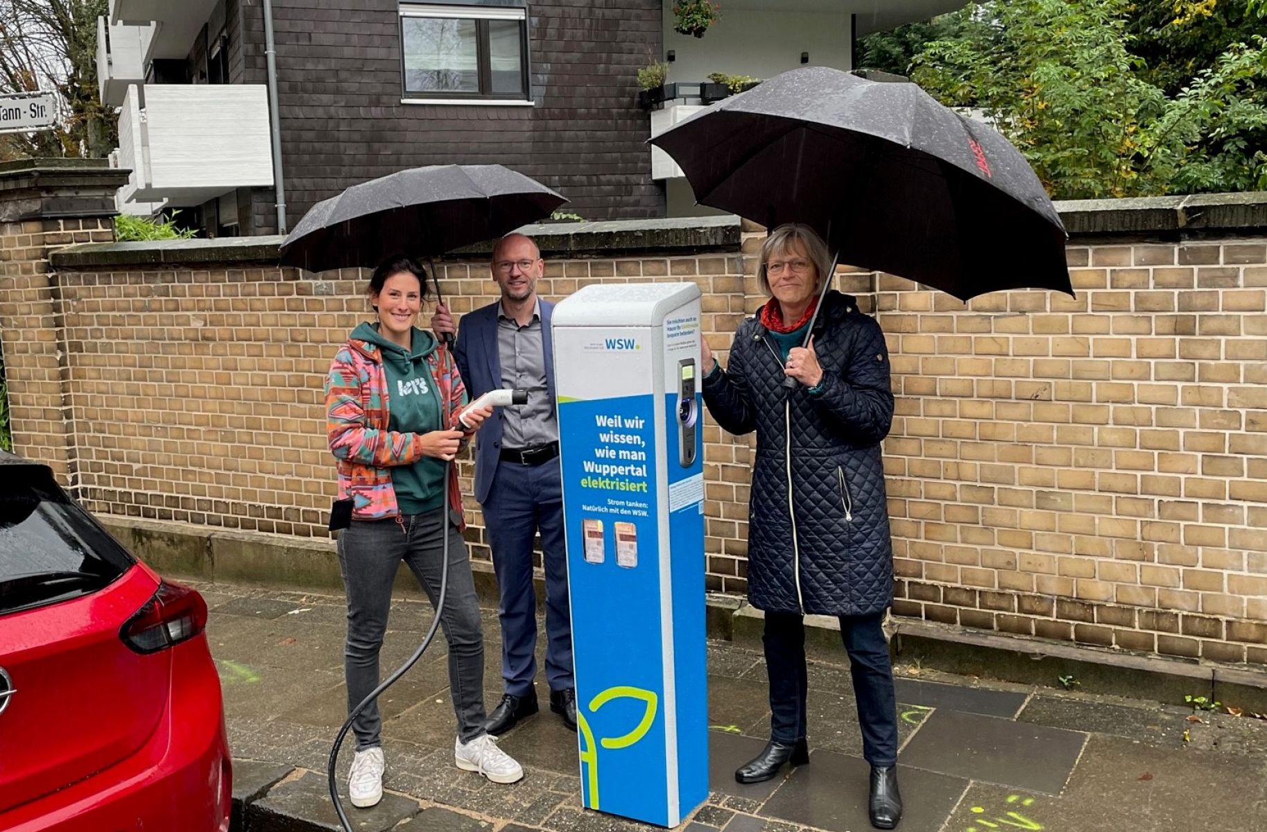 Linda Arendt (links) lädt ihr Elektroauto auf. Daneben: Andy Völschow (Leiter Kunden- & Quartierslösungen bei den WSW), Gabriele Mahnert (ehemalige Bezirksbürgermeisterin Elberfeld-West)